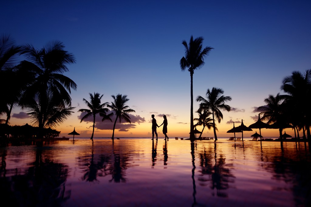 Silhouettes of young couple at scenic sunset on tropical beach